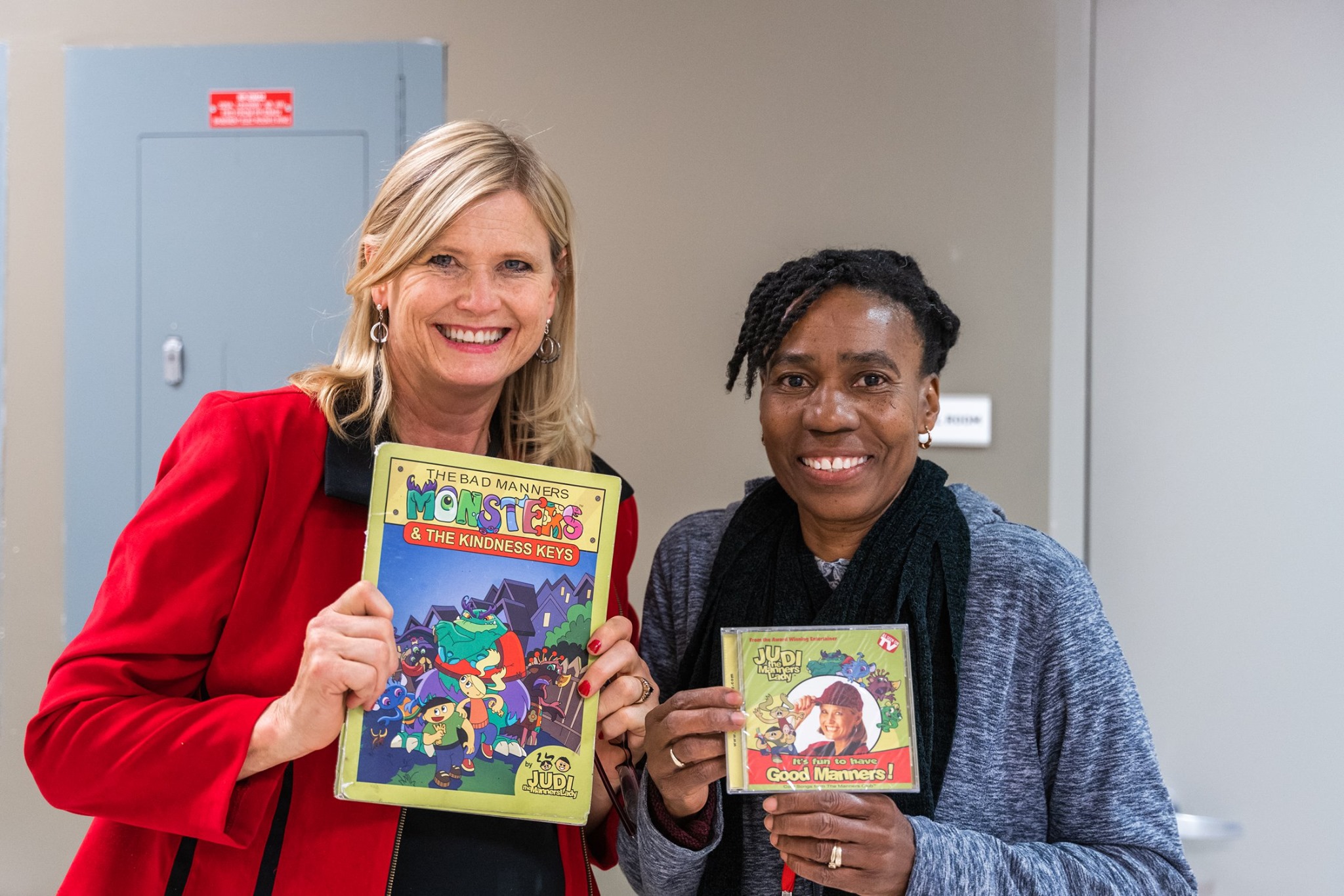 Two participants holding a children book and a CD respectively