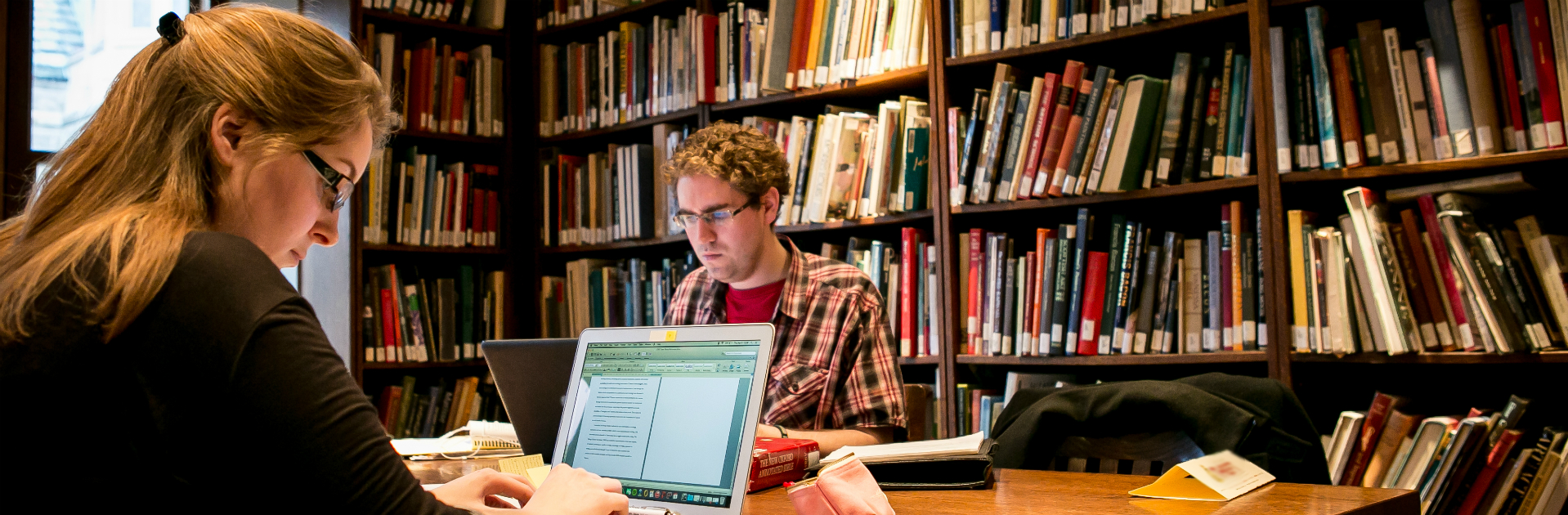 Library with man and woman typing on laptops at a desk