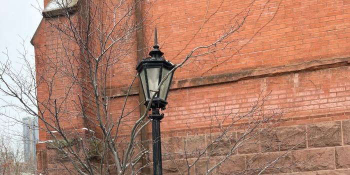 lampstand in winter against WC red brick wall, facing Great Hall