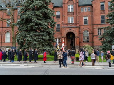 2024 Convocation graduates in robes outside front steps