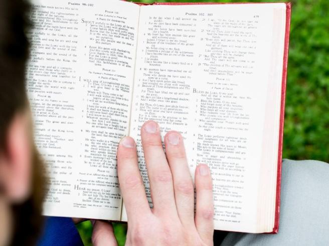 Aidan Armstrong reading Bible on front lawn Principal's Lodge 