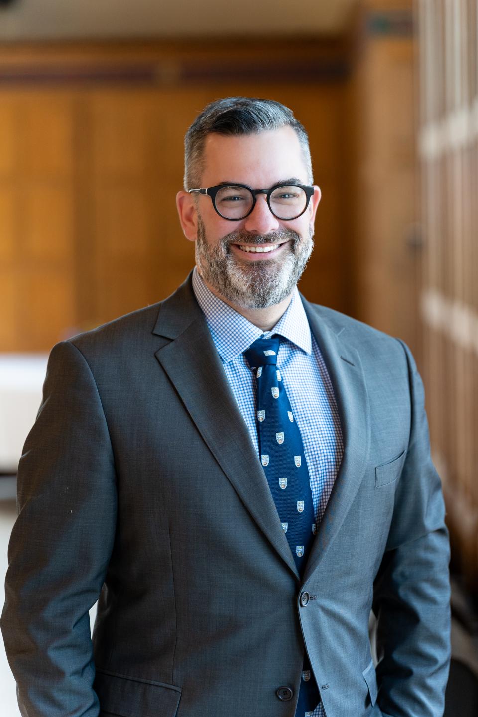 Dr Justin Stratis in Great Hall against wood panelling (2025)