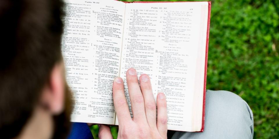 Aidan Armstrong reading Bible on front lawn Principal's Lodge 